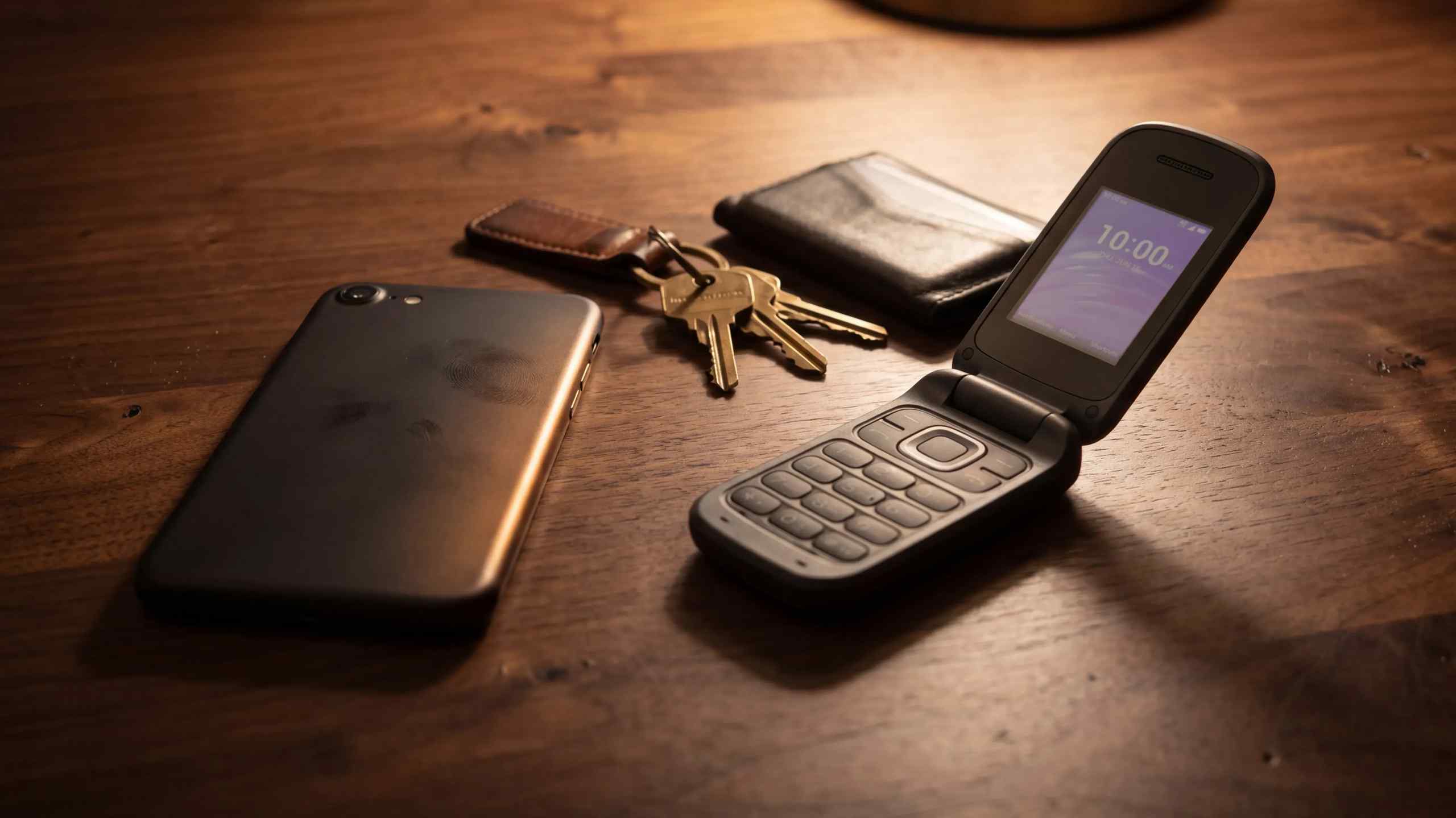 A smartphone, keys, wallet and an old-school flip phone.